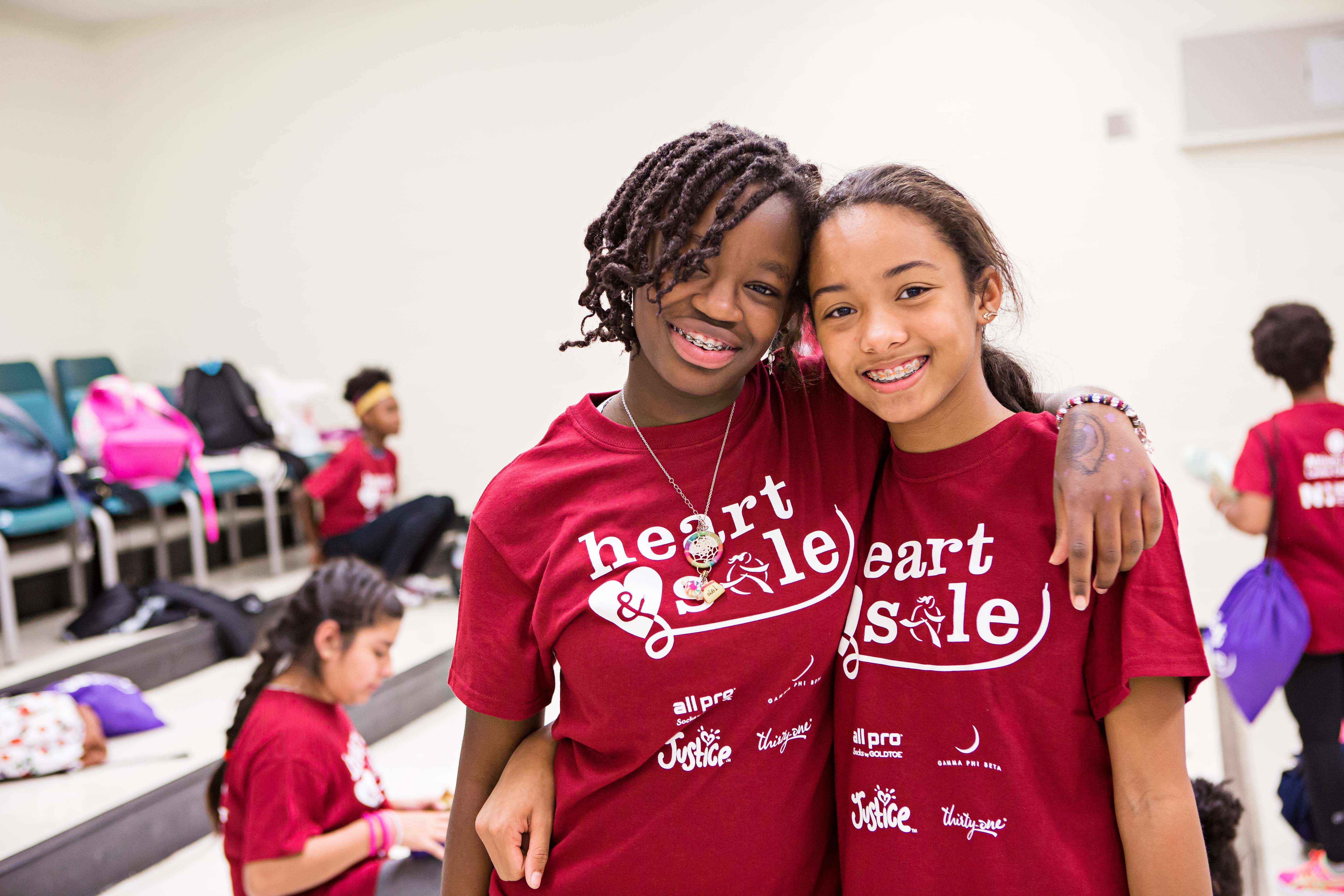 Two girls in red shirts hugging.